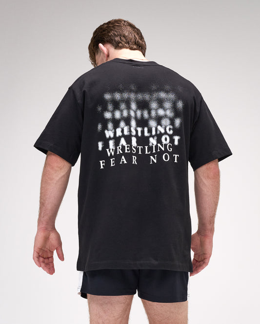 Person wearing a black t-shirt with 'Wrestling Fear Not' text on the back, standing against a plain background.