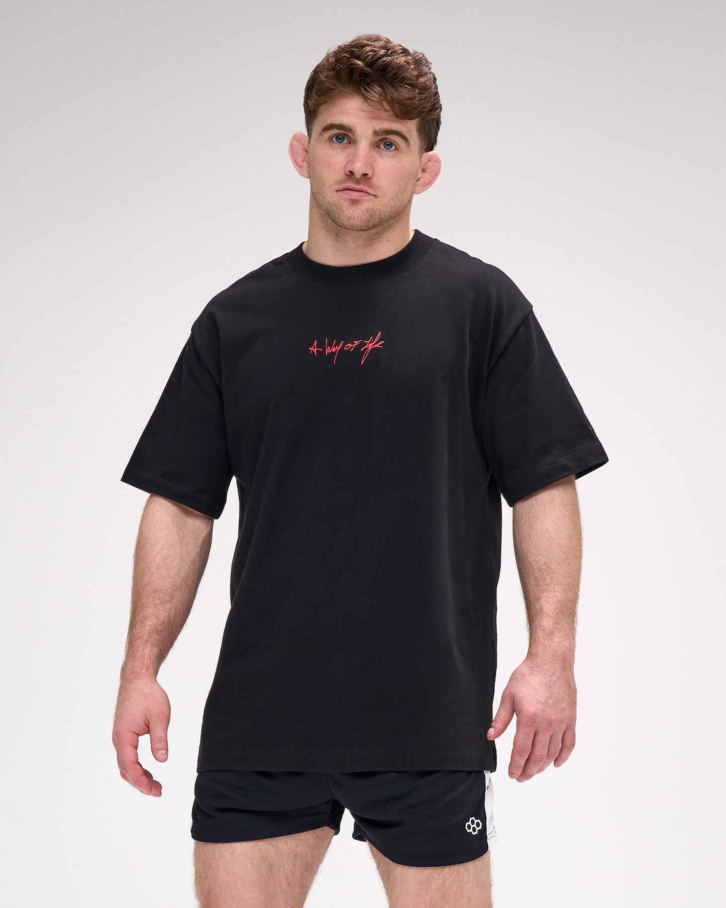 Man wearing a black t-shirt with red 'A Way of life' text and black shorts on a white background
