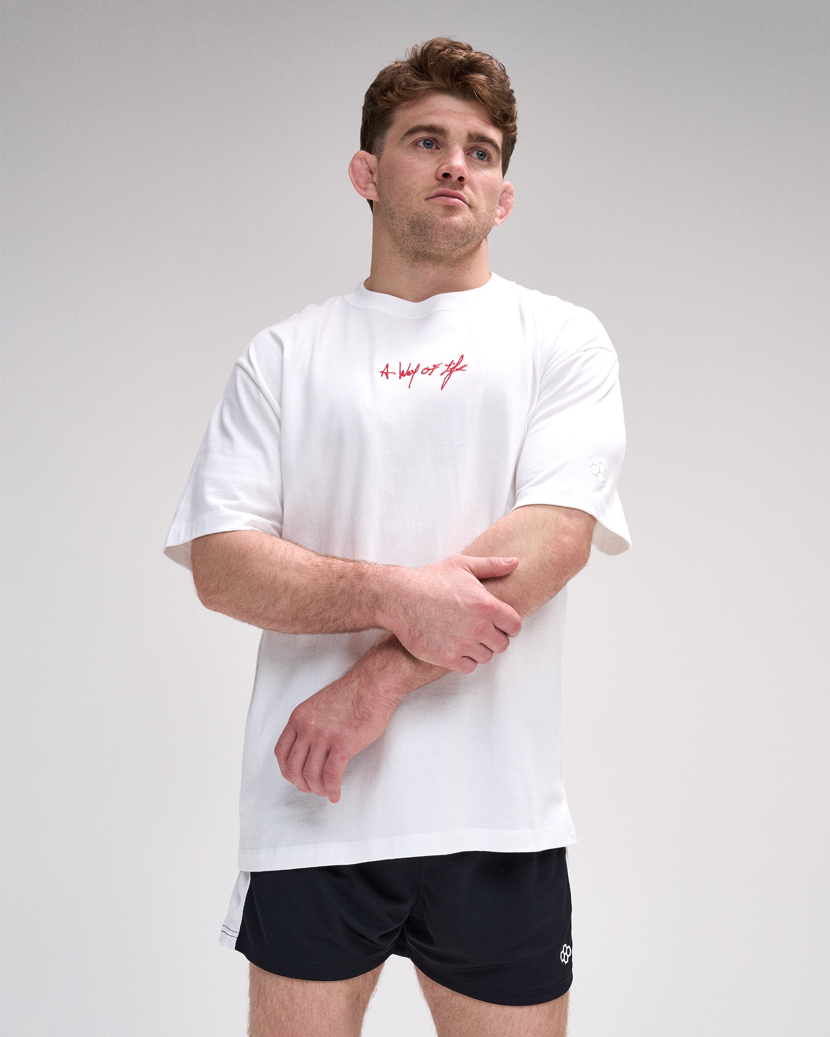 Man wearing a white t-shirt with red 'A way of life' text and black shorts on a gray background