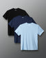 Three short-sleeve crewneck t-shirts from RUDIS, shown in black, navy blue, and light blue, arranged in a layered fan layout on a gray gradient background.