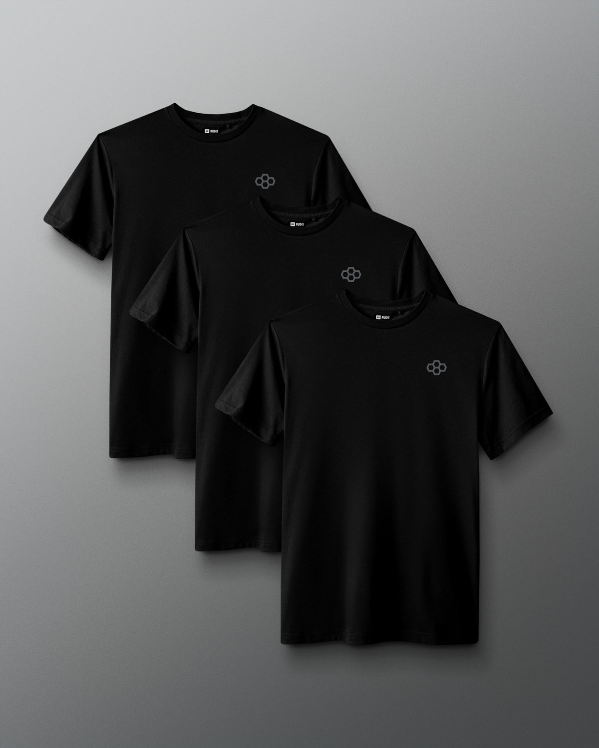 Three black short-sleeve crewneck t-shirts with a small white geometric logo on the left chest, arranged in a staggered overlapping layout on a dark gray gradient background.