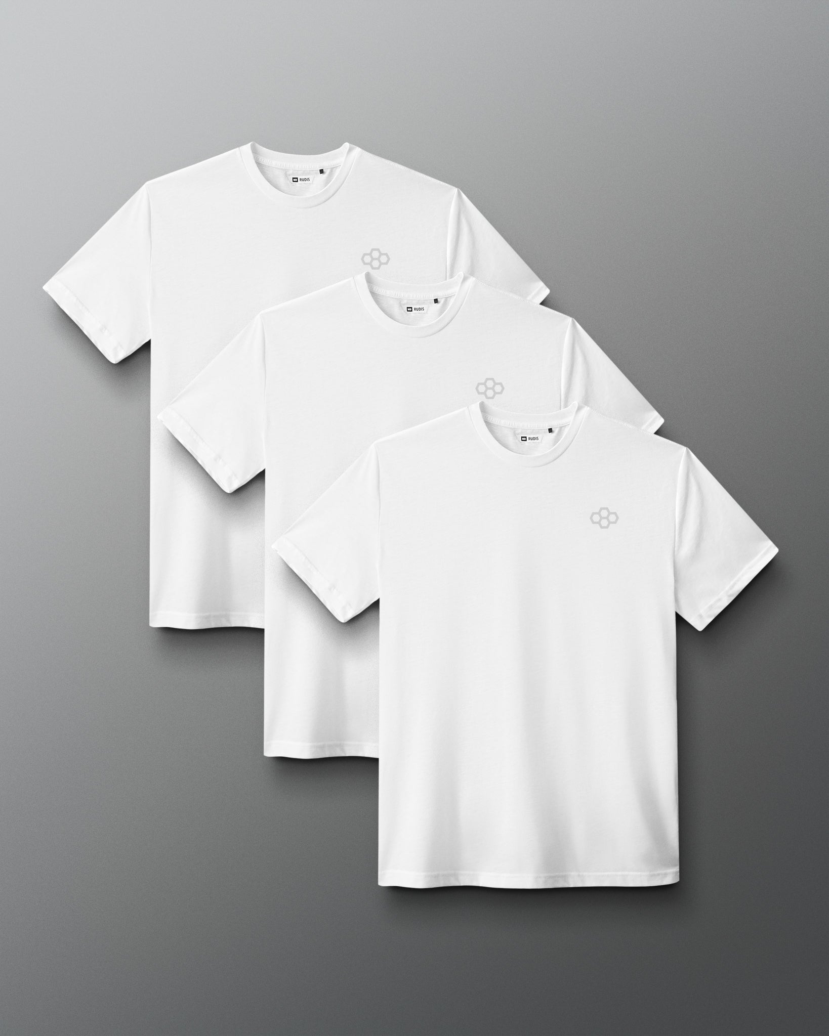Three white short-sleeve crewneck t-shirts with a small gray geometric logo on the left chest, arranged in a staggered overlapping layout on a dark gray gradient background.