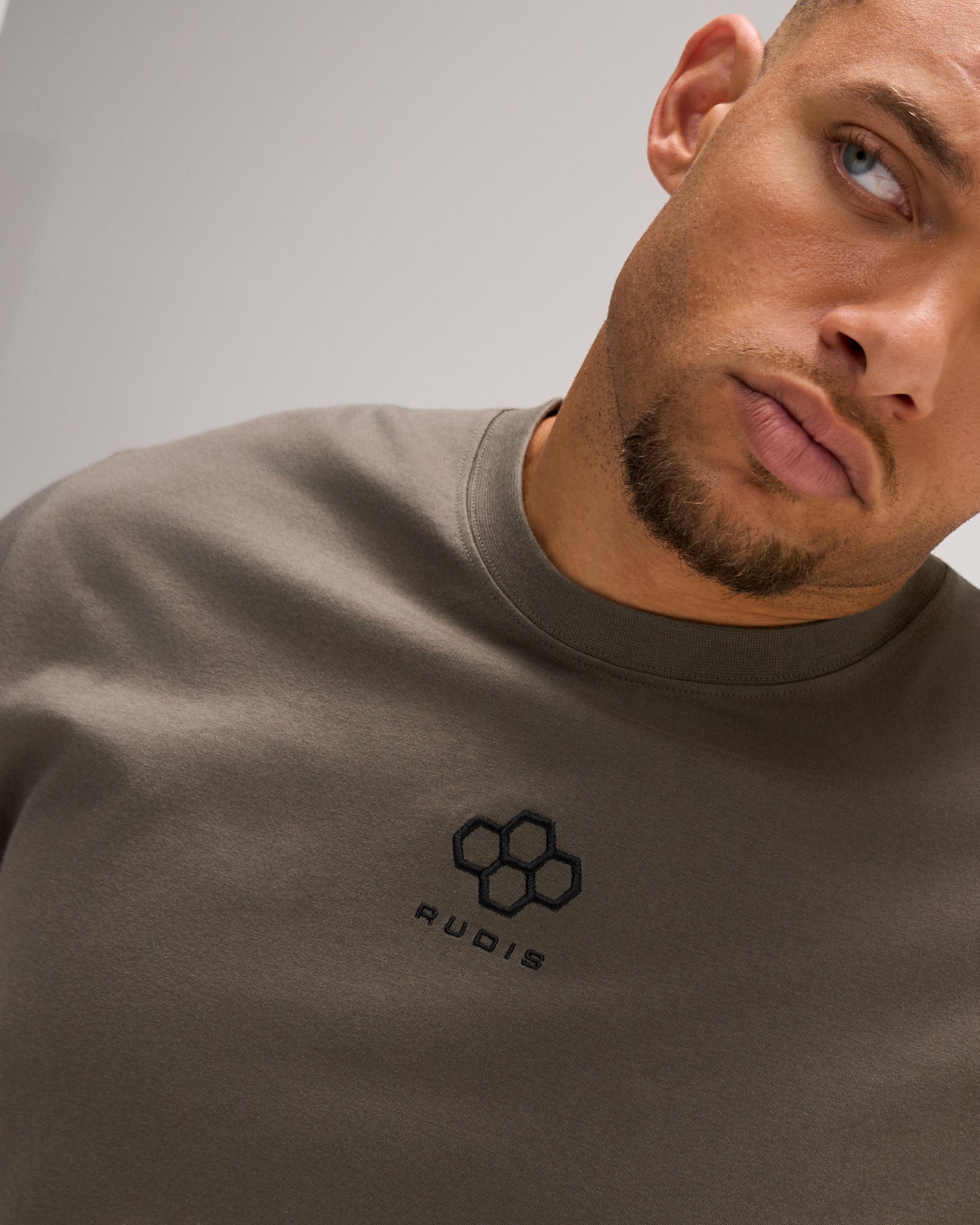 Detailed close-up of the RUDIS Hex Classic Cotton T-Shirt in Army, showcasing the black embroidered Hex logo, cotton fabric and ribbed crew neckline.
