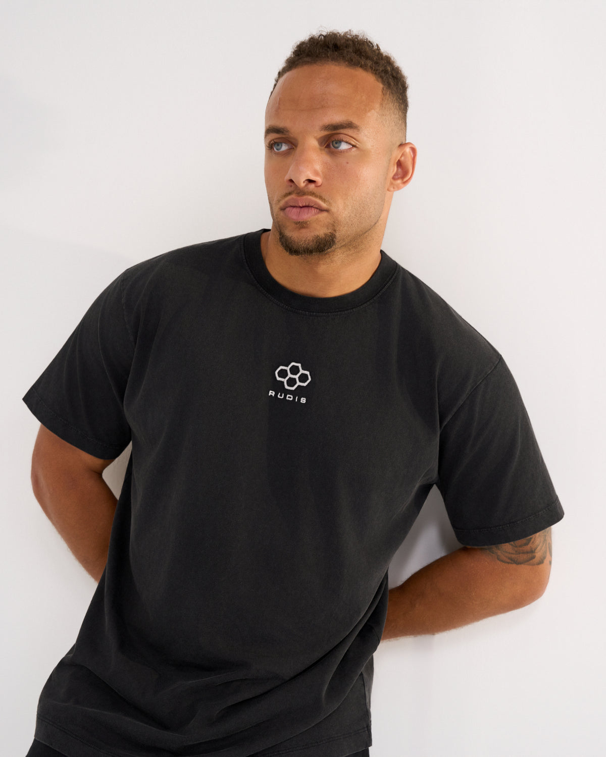 Male model wearing the RUDIS Hex Classic Cotton T-Shirt in Washed Black, featuring white embroidered Hex chest branding, short sleeves and a relaxed fit.