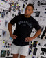 Male model standing in the RUDIS Wrestling Classic Cotton T-Shirt in Black, featuring a vintage-style Wrestling chest graphic and relaxed silhouette.
