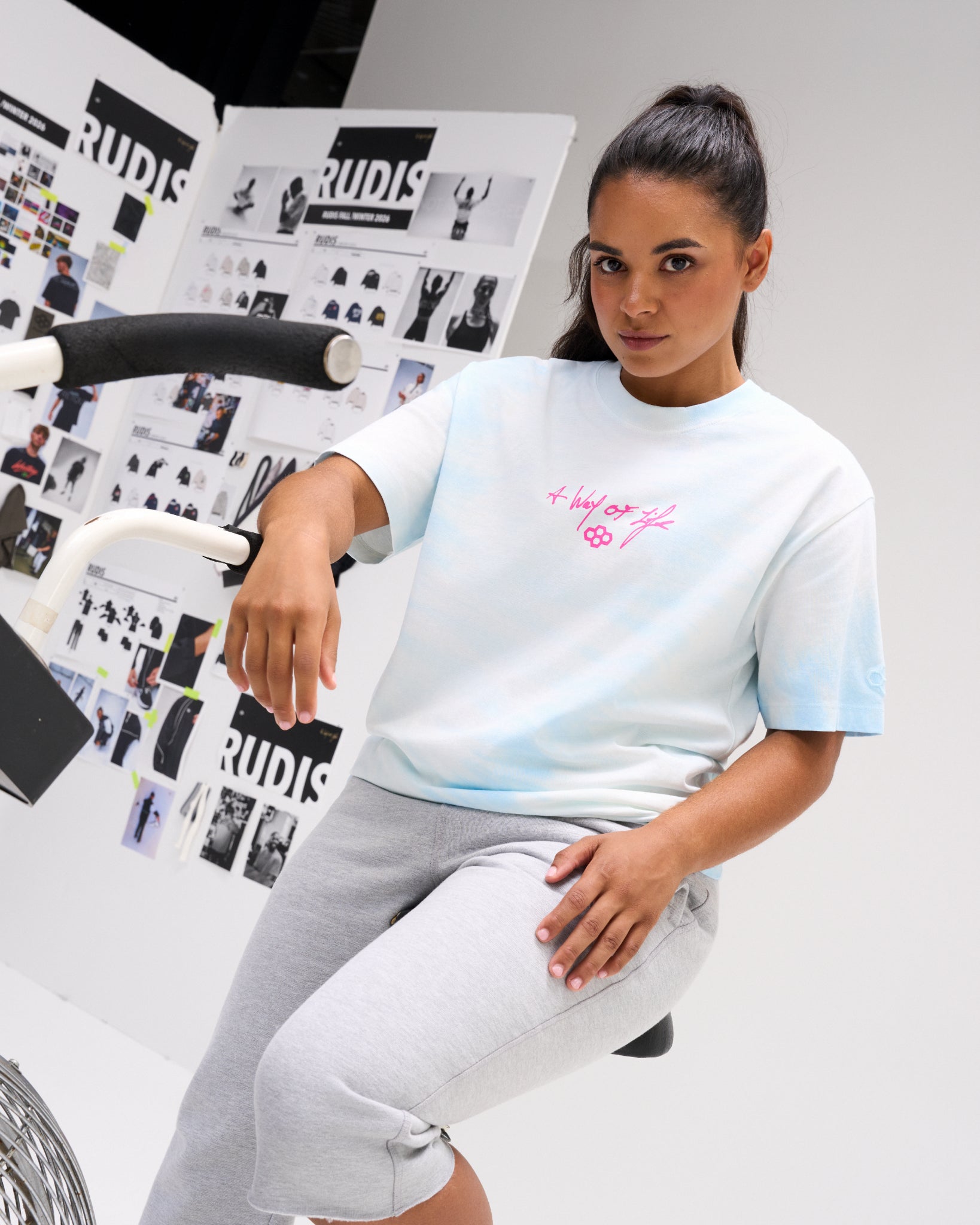 Female model wearing the RUDIS Faith Over Fear Classic Cotton T-Shirt in Blue Tie Dye with a pink A Way of Life chest graphic and RUDIS Hex logo.