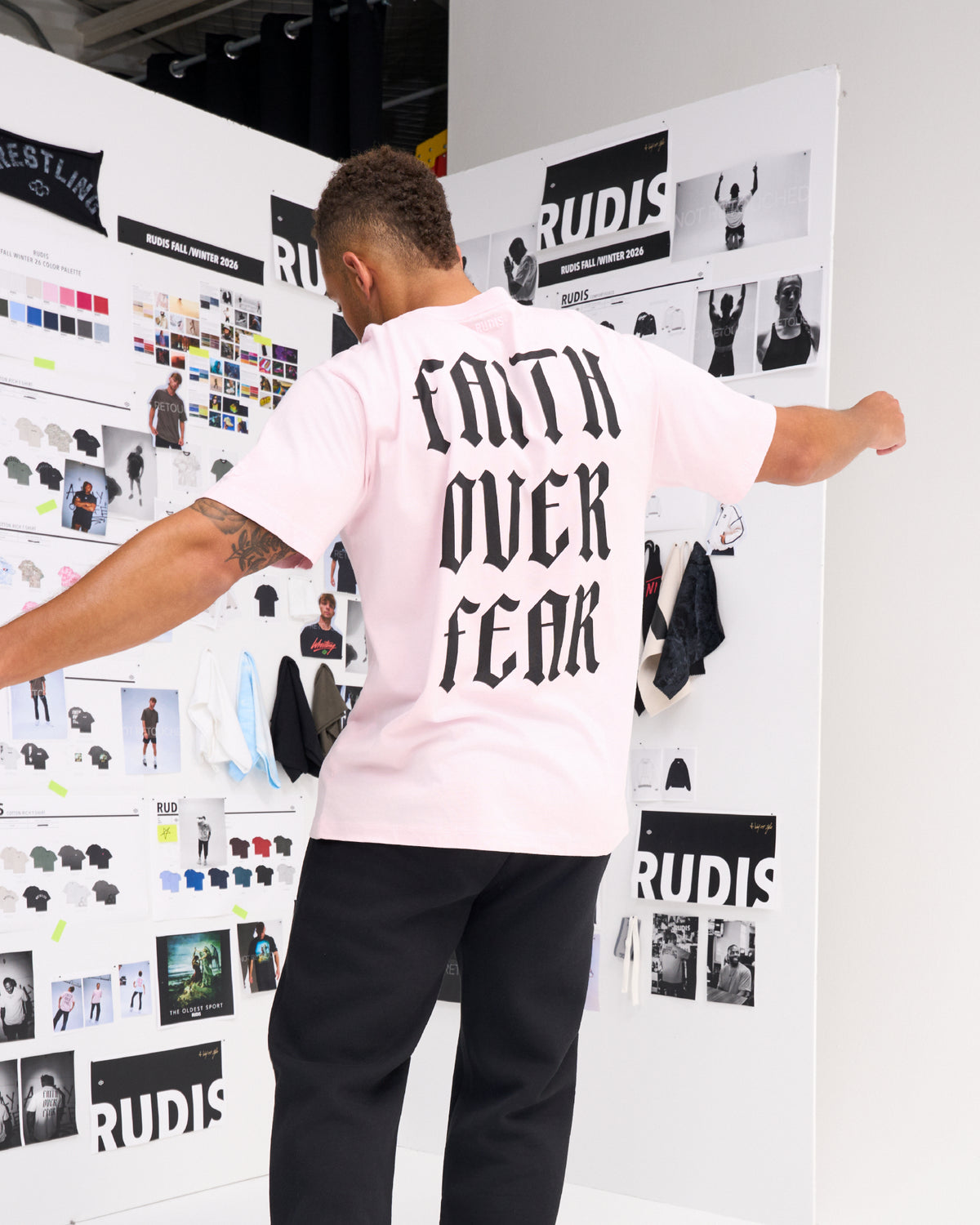 Male model wearing the RUDIS Faith Over Fear Classic Cotton T-Shirt in Washed Pink, showcasing oversized black Faith Over Fear lettering on the back.