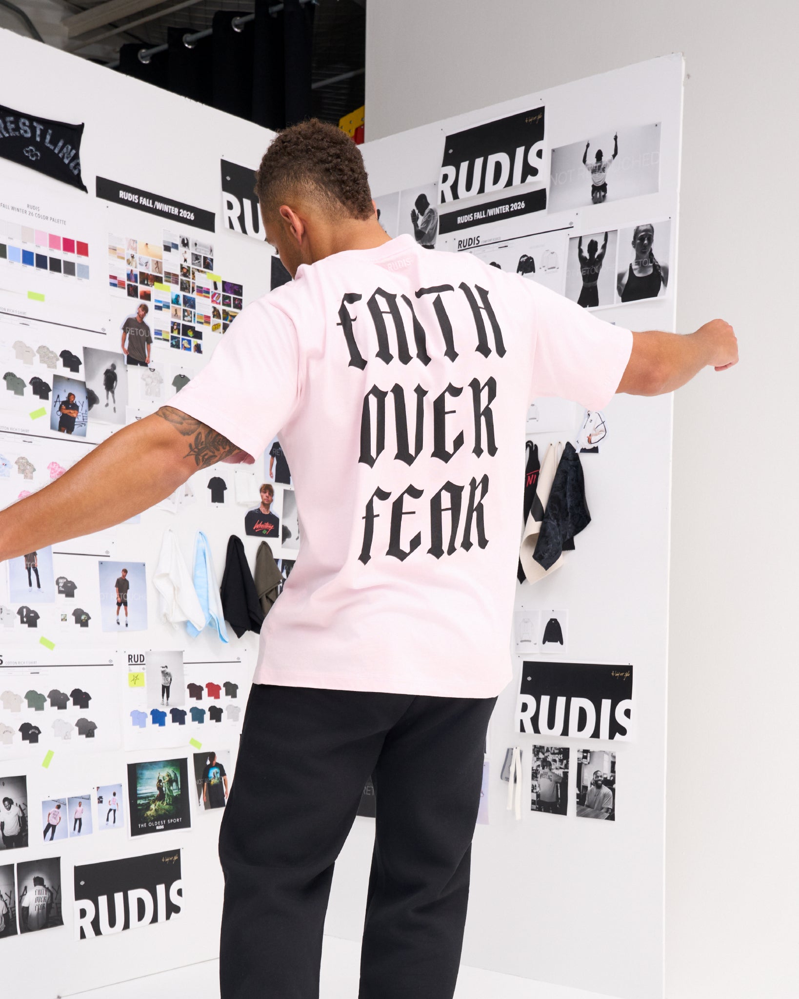 Male model wearing the RUDIS Faith Over Fear Classic Cotton T-Shirt in Washed Pink, showcasing oversized black Faith Over Fear lettering on the back.