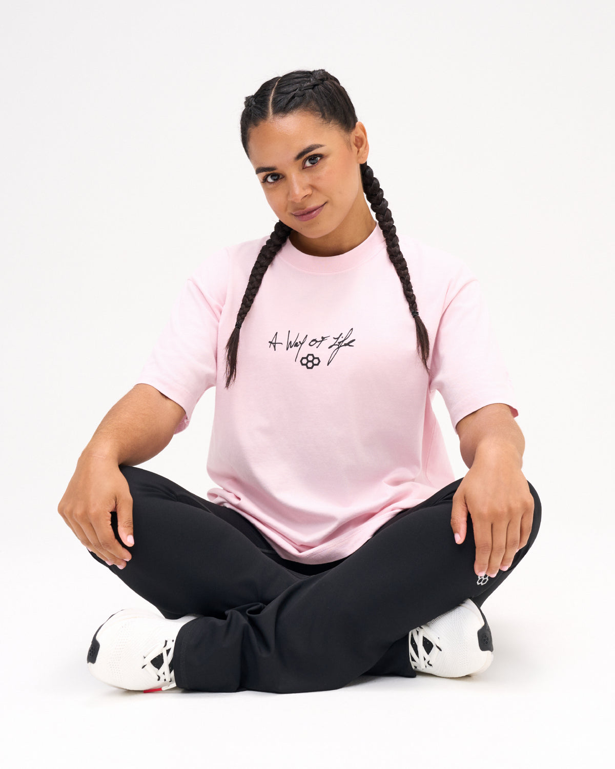 Female model seated in the RUDIS Faith Over Fear Classic Cotton T-Shirt in Washed Pink, featuring black A Way of Life script and the RUDIS Hex logo.
