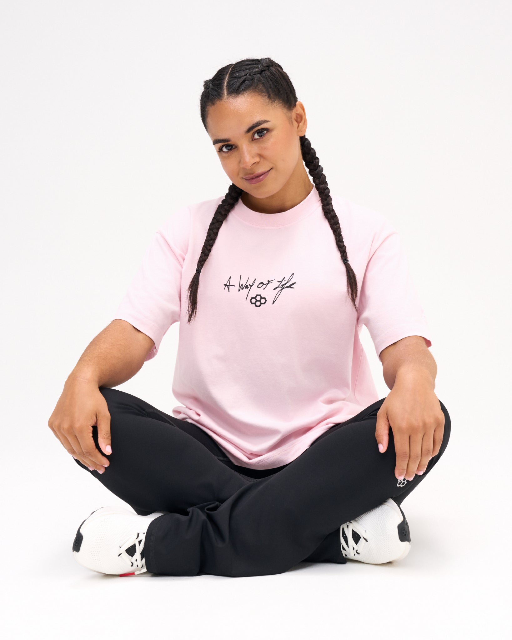 Female model seated in the RUDIS Faith Over Fear Classic Cotton T-Shirt in Washed Pink, featuring black A Way of Life script and the RUDIS Hex logo.