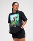 Female model wearing the RUDIS Divine Struggle Relaxed Cotton T-Shirt in Washed Black, showcasing vintage-inspired wrestling artwork, The Oldest Sport text, and a relaxed fit.