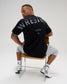 Male model seated wearing the RUDIS Wrestling Back Relaxed Cotton T-Shirt in Black, featuring a large distressed WRESTLING back print and A Way of Life message.