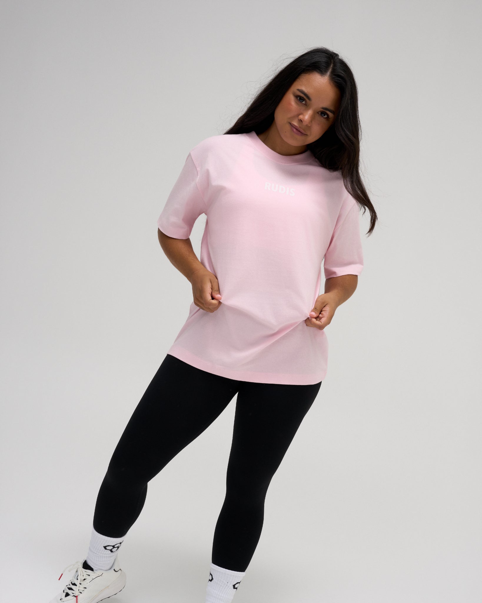 Female model wearing the RUDIS Wrestling Back Relaxed Cotton T-Shirt in Washed Pink, featuring a small white RUDIS chest logo, crew neckline, and relaxed fit.