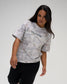 Female model wearing the RUDIS Relaxed Cotton T-Shirt in light gray tree camo with a gray RUDIS chest logo and black athletic pants.