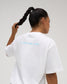 Back view of female model wearing the white RUDIS Relaxed Cotton T-Shirt with light blue A WAY OF LIFE lettering across the upper back.