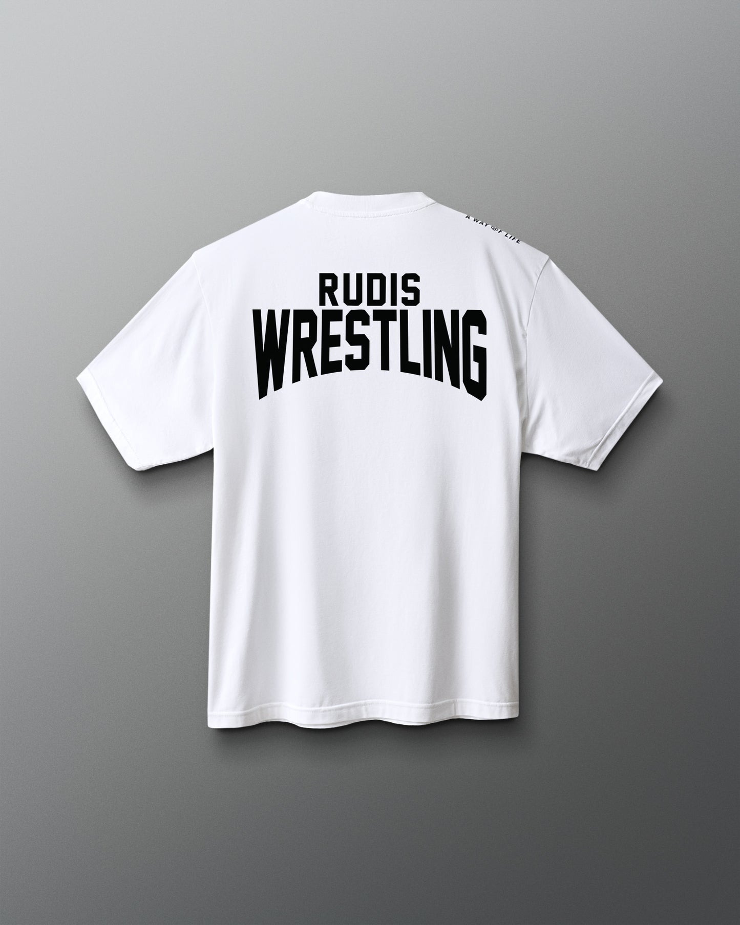 A white short-sleeve t-shirt shown from the back, featuring the words 'RUDIS WRESTLING' printed in bold black letters across the upper back, set against a dark gray gradient background.