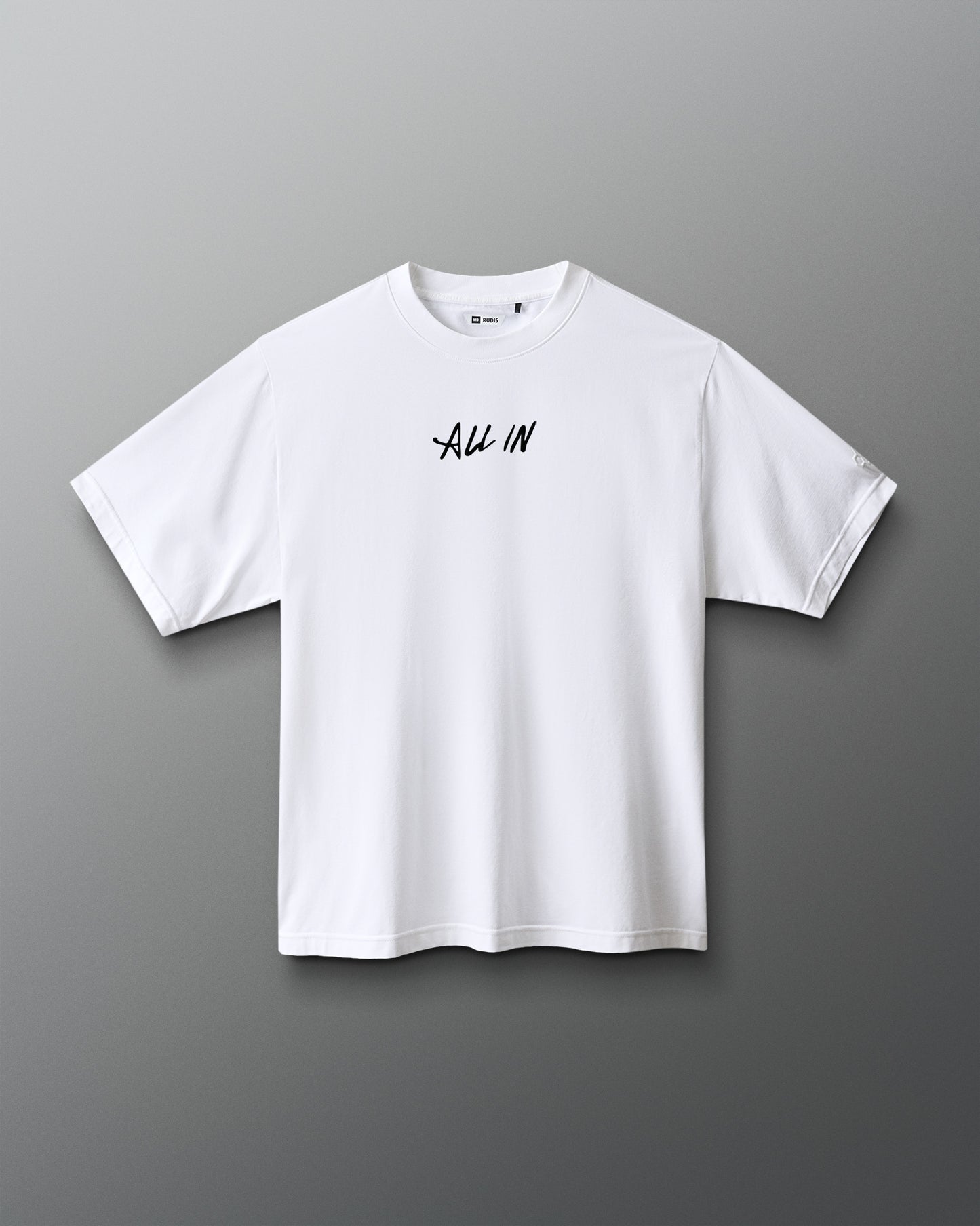 A white short-sleeve crewneck t-shirt with the words 'ALL IN' printed in black script across the chest, displayed against a dark gray gradient background.