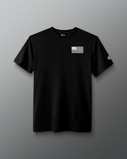 Black RUDIS Core Flag Elite Super Soft T-Shirt shown from the front, featuring a white American flag graphic on the chest and RUDIS mark on the sleeve.