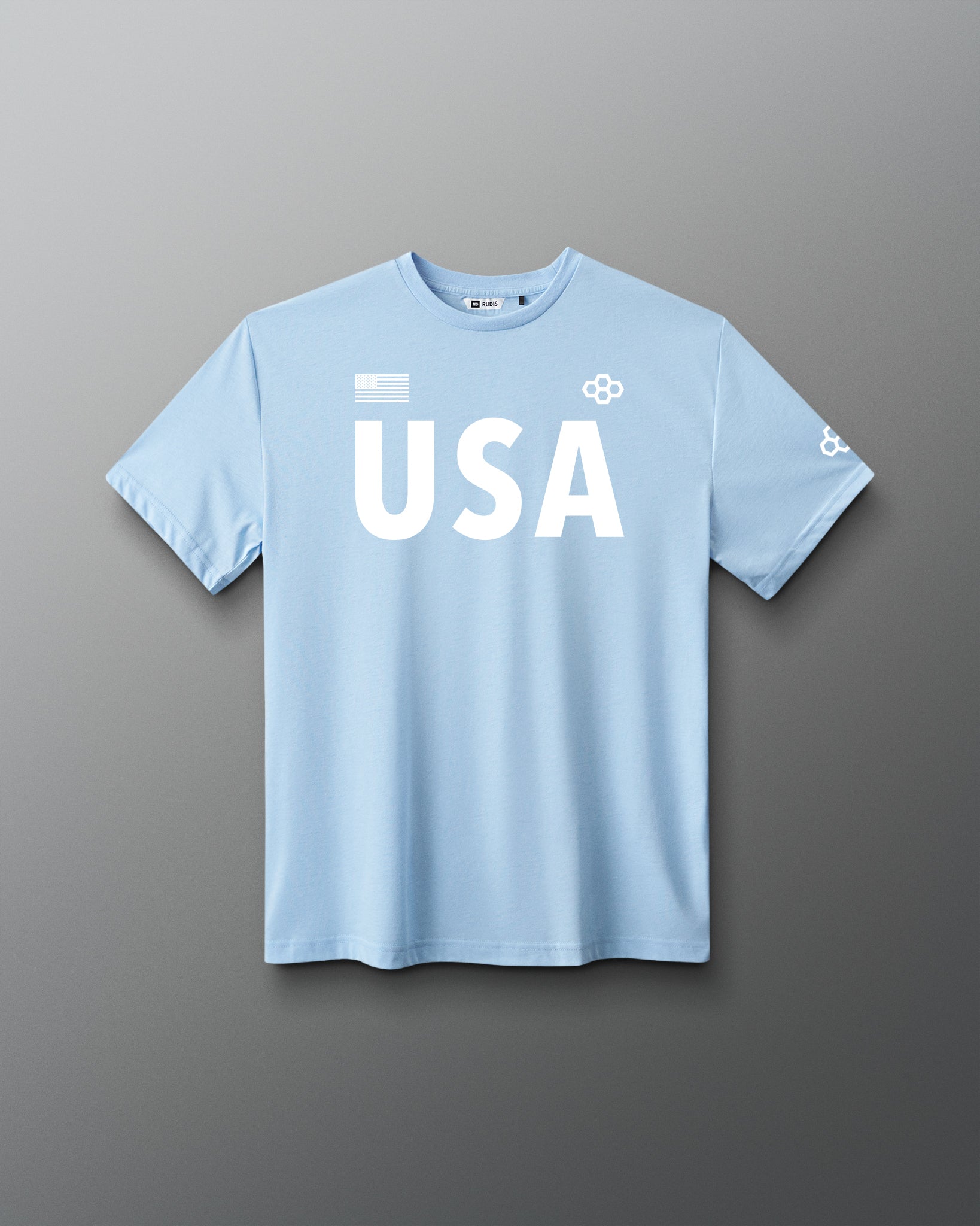 Front view of RUDIS USA Elite Super Soft T-Shirt in light blue, showcasing white USA lettering, American flag graphic, RUDIS Hex logos, and short sleeves.