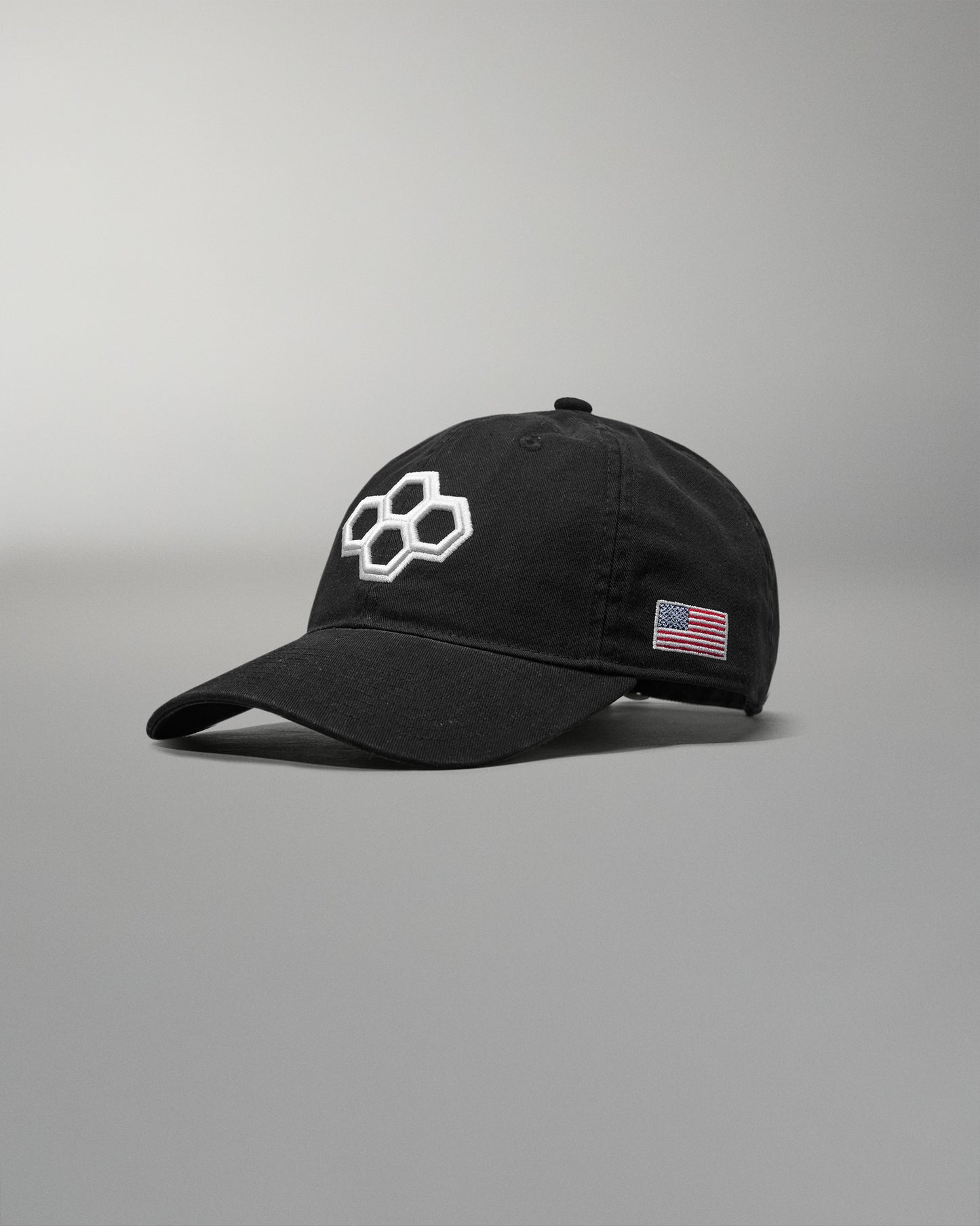Black cap with a logo and American flag patch on a gray background