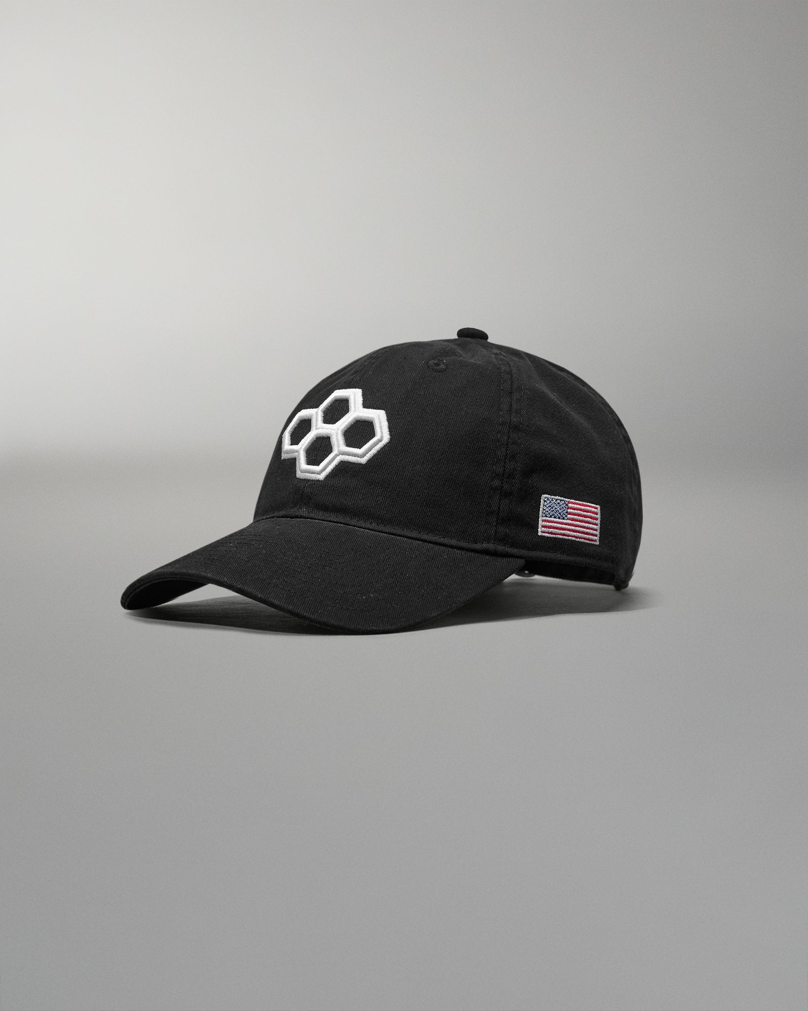 Black cap with a logo and American flag patch on a gray background