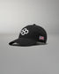 Black cap with a logo and American flag patch on a gray background