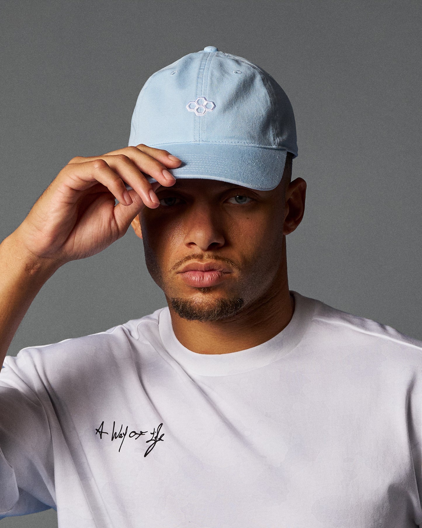 Man wearing a light blue cap and white t-shirt with text on a gray background