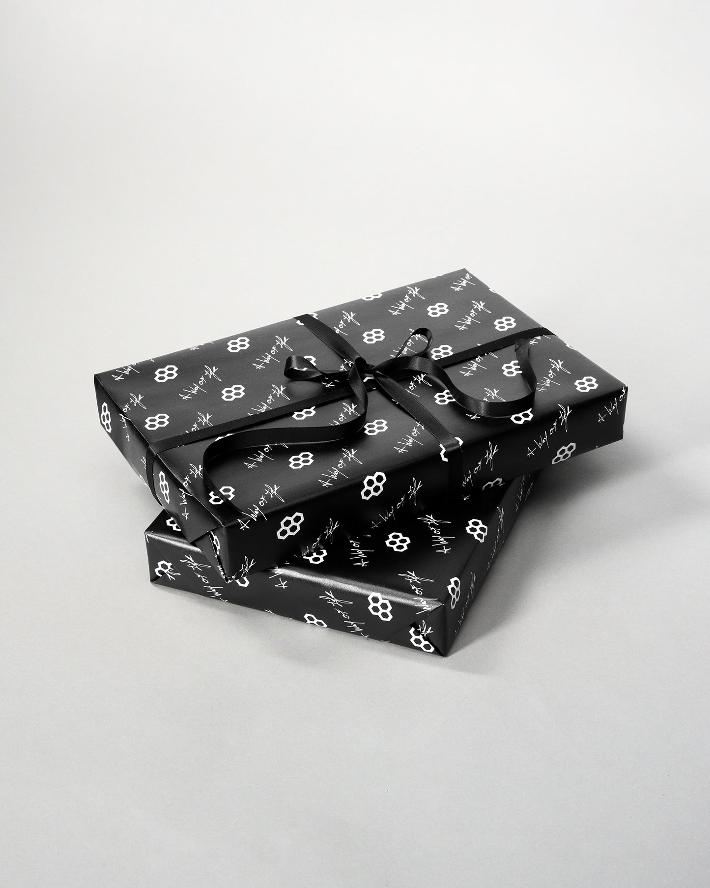 Two black gift boxes with white floral patterns on a light gray background