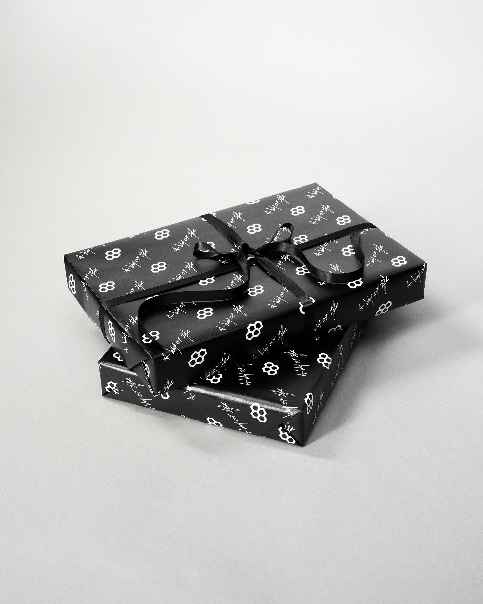 Two black gift boxes with white floral patterns on a light gray background