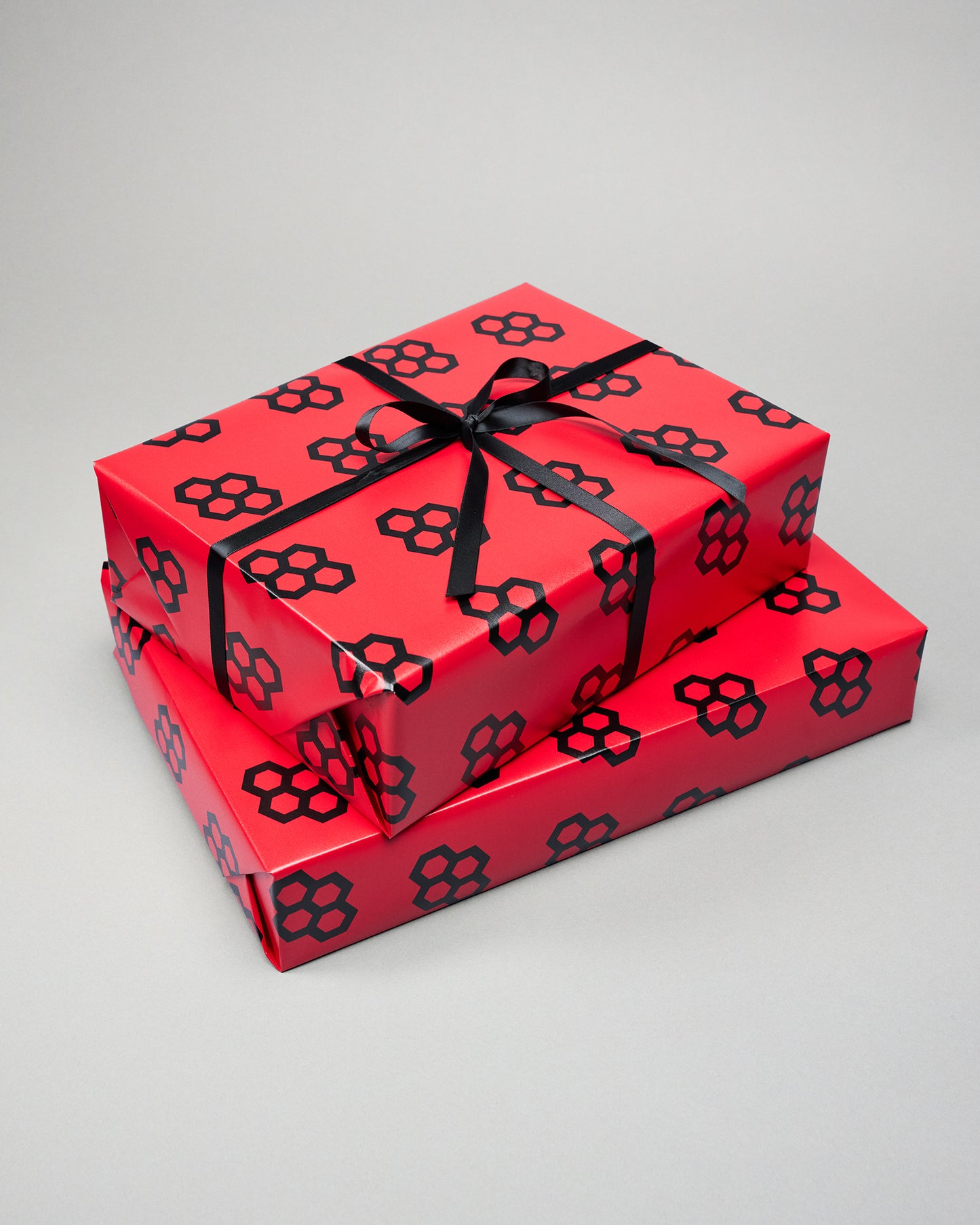 Two red gift boxes with black floral patterns and ribbons on a gray background