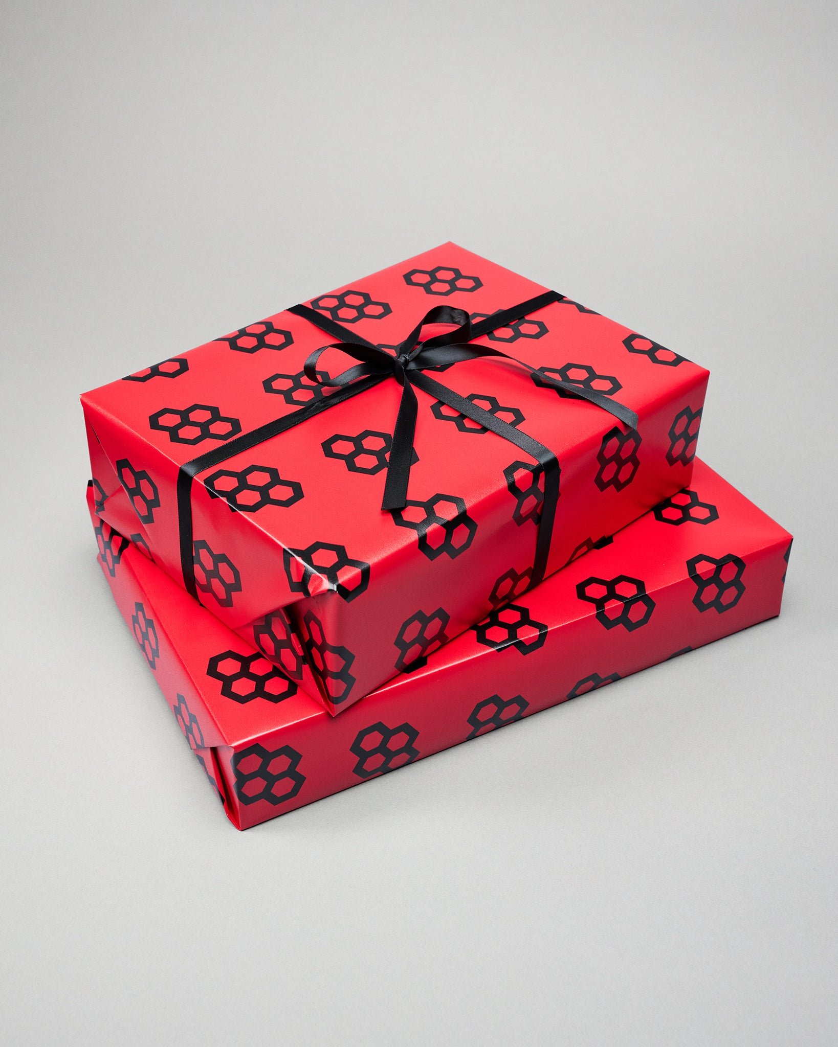 Two red gift boxes with black floral patterns and ribbons on a gray background