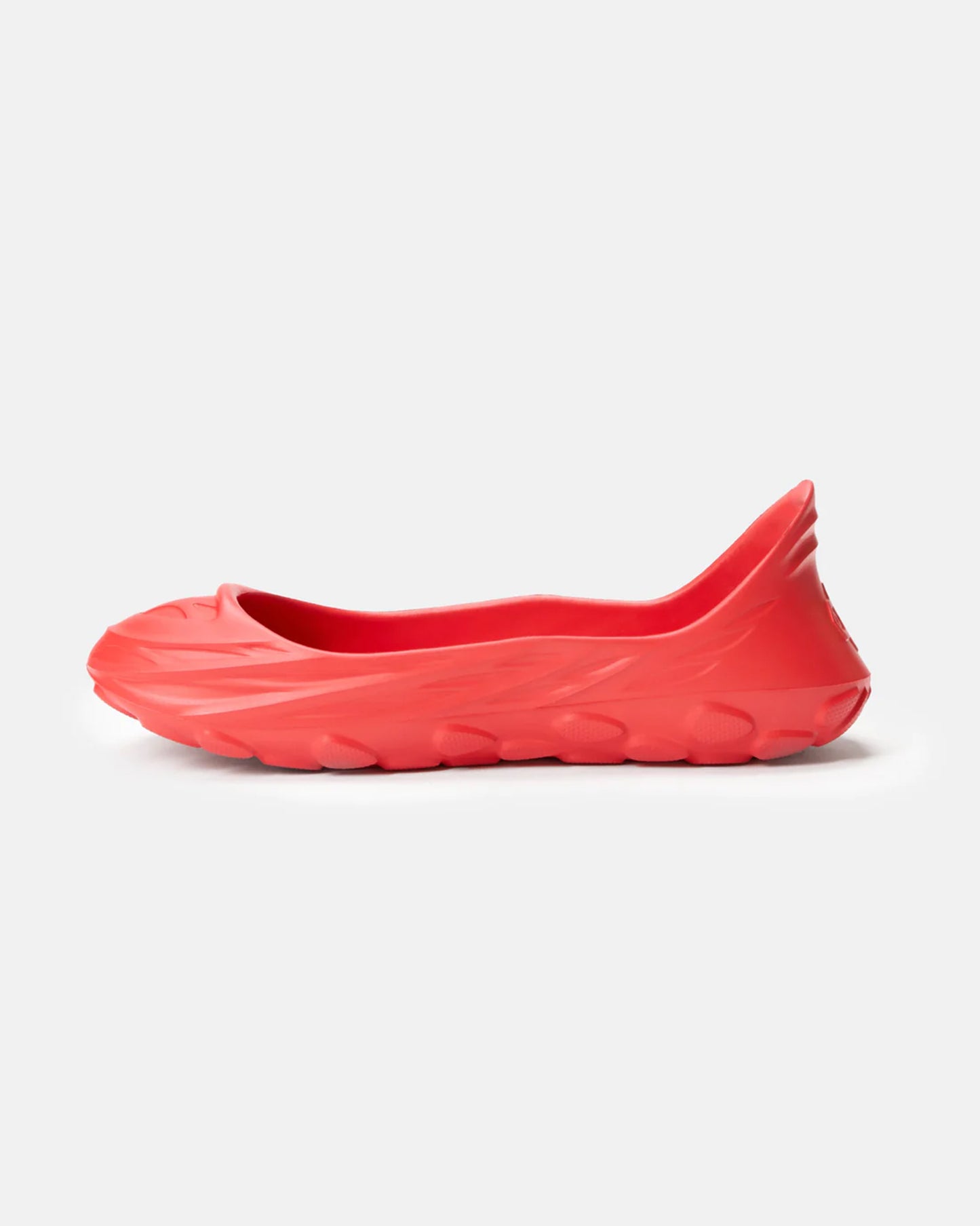 A vibrant red slip-on shoe featuring a sleek fluid design and a textured sole ideal for casual wear and comfort