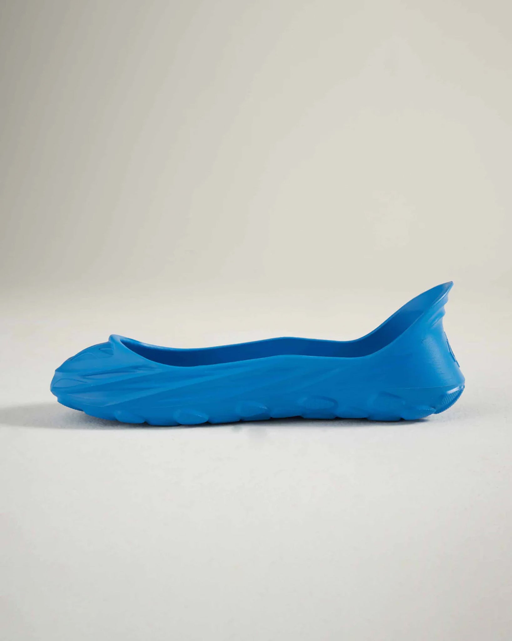 A sleek blue slip-on shoe with a minimalist design and contoured shape perfect for casual or light outdoor activities