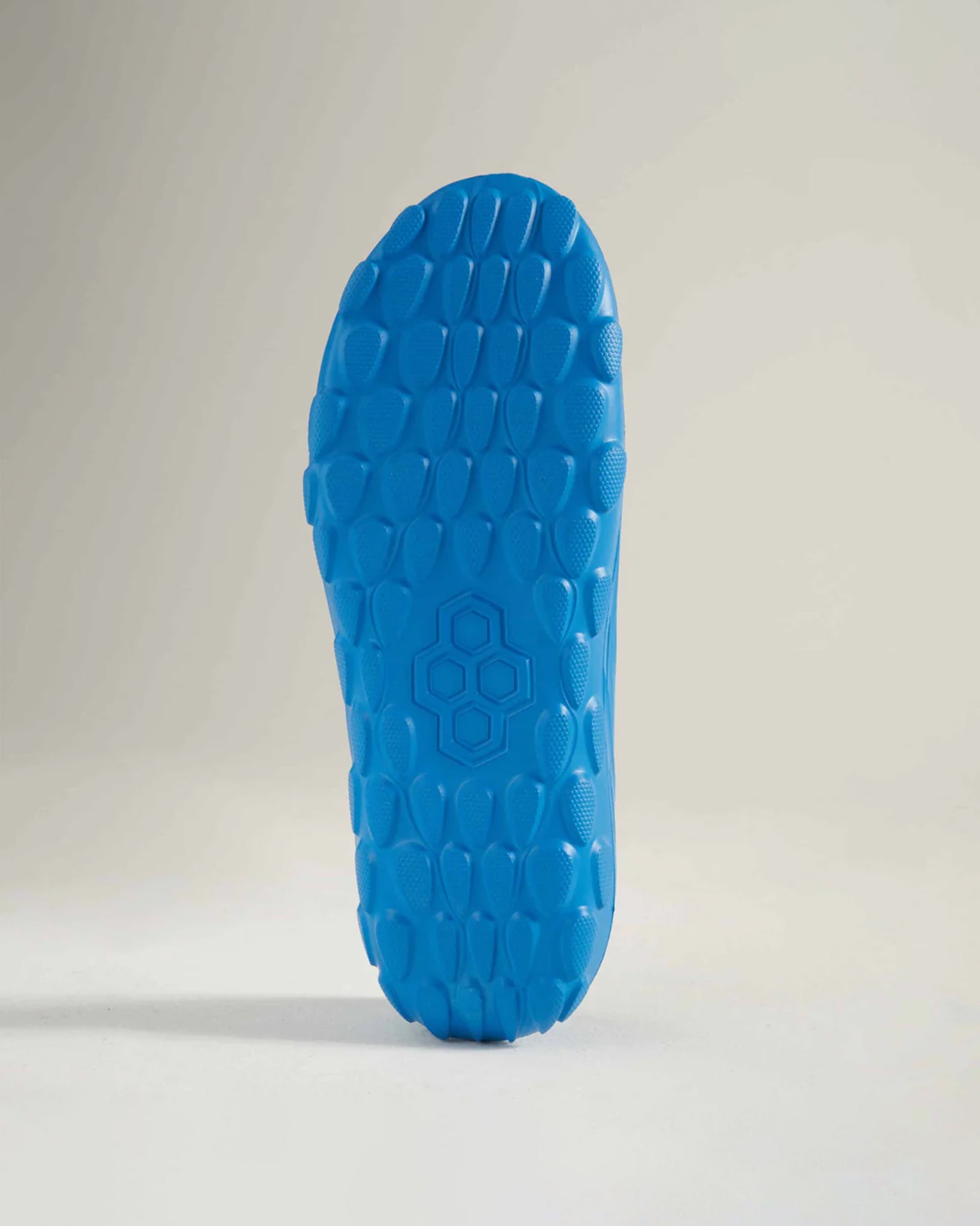 The image displays a vibrant blue shoe sole featuring a textured grip pattern designed for optimal traction on various surfaces
