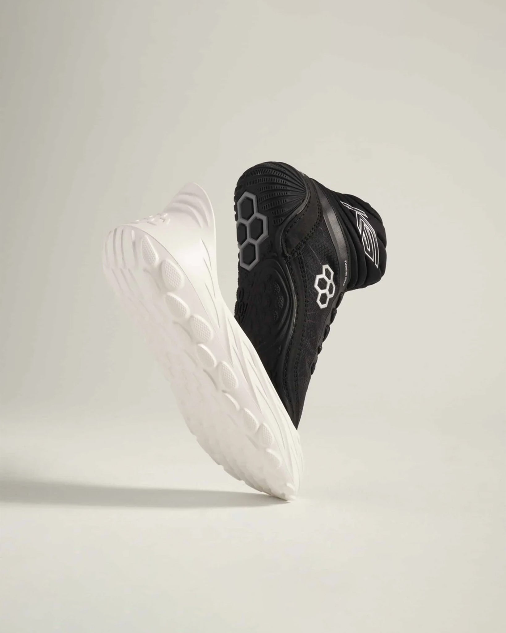 A pair of modern athletic shoes in black and white with dynamic design elements showcasing their unique textured soles and sleek silhouette