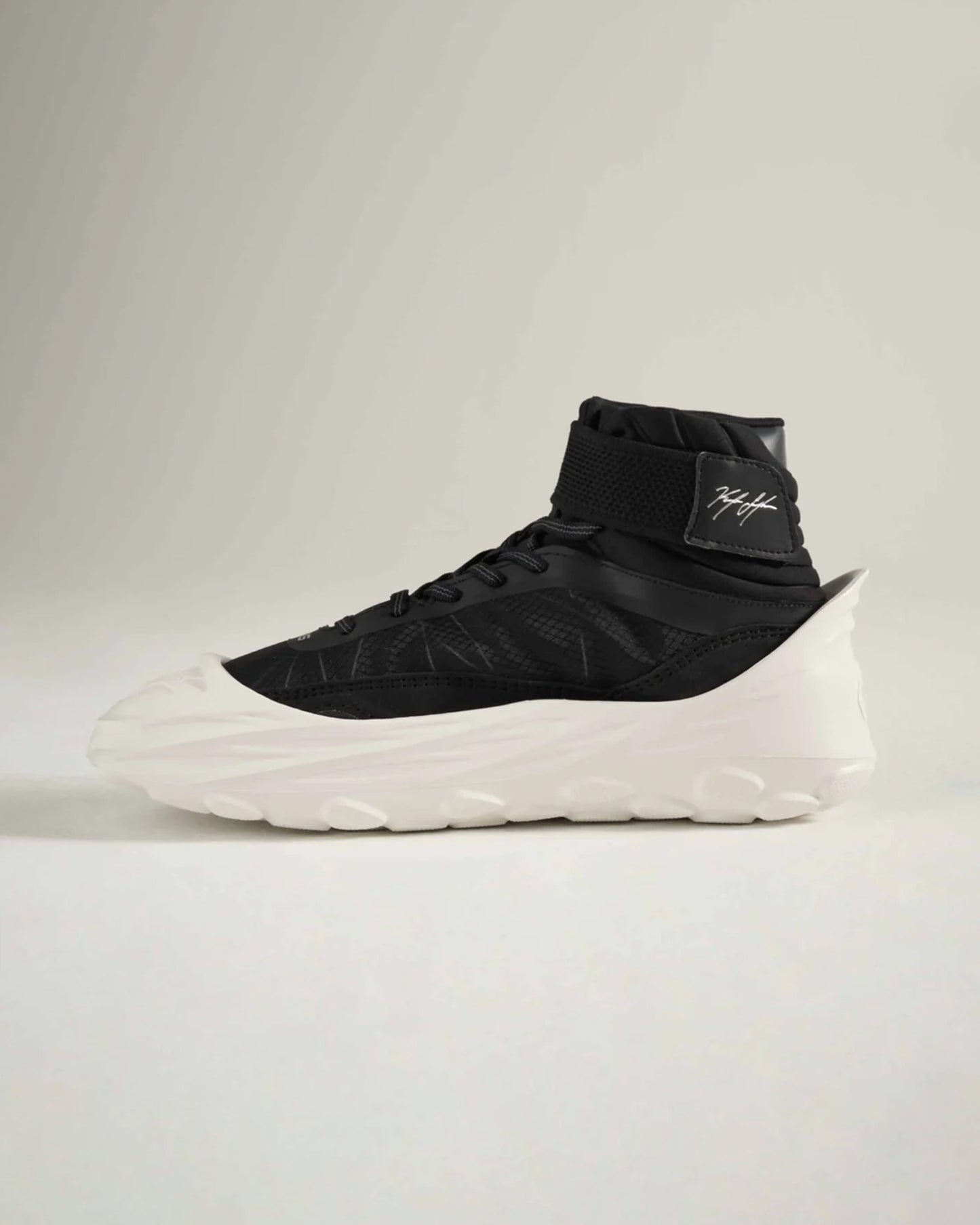 A contemporary high-top sneaker featuring a black mesh upper a neoprene collar for a snug fit and a thick white sole with textured detailing for enhanced grip