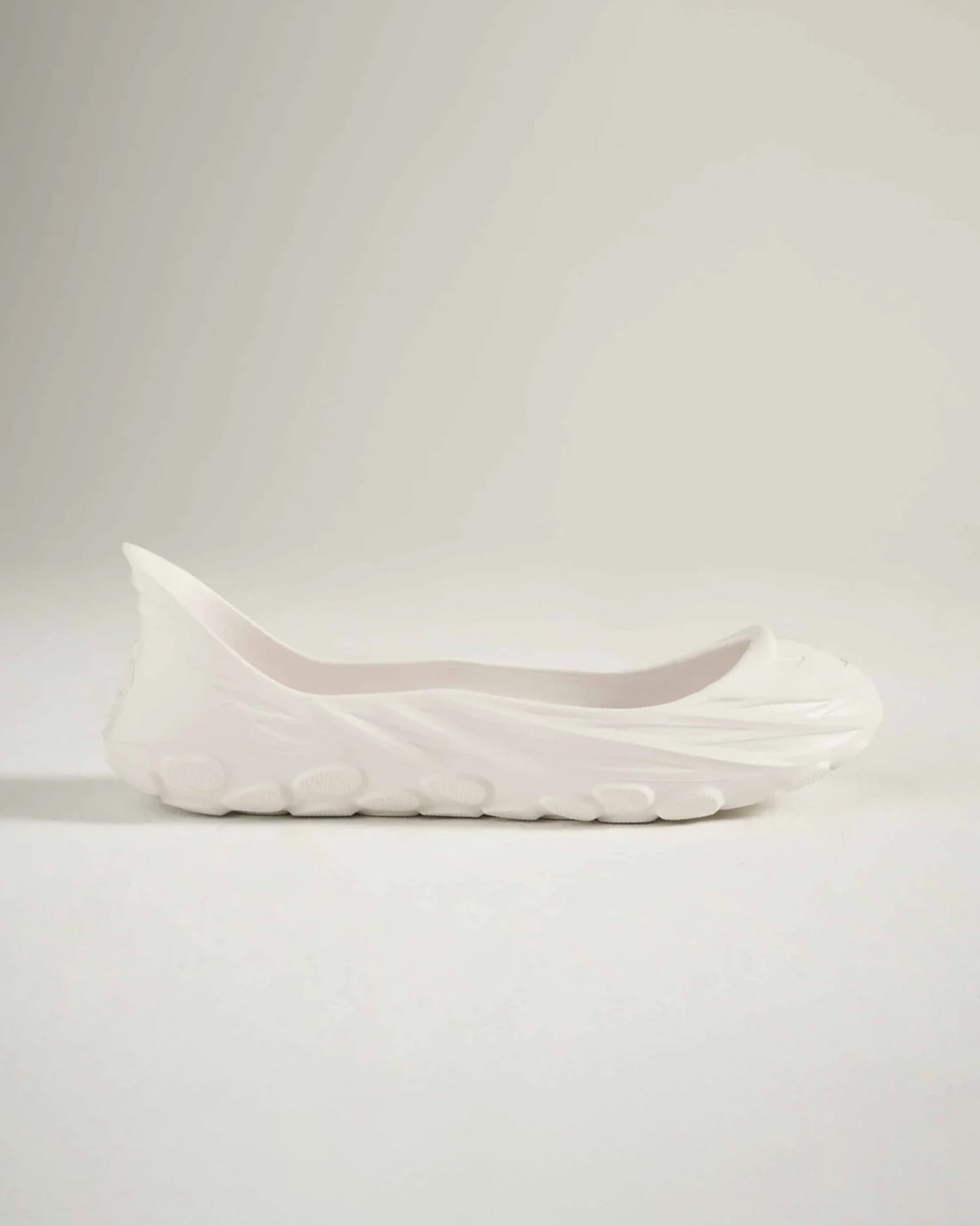 A sleek white slip-on shoe featuring a modern design and textured sole perfect for casual wear and comfort