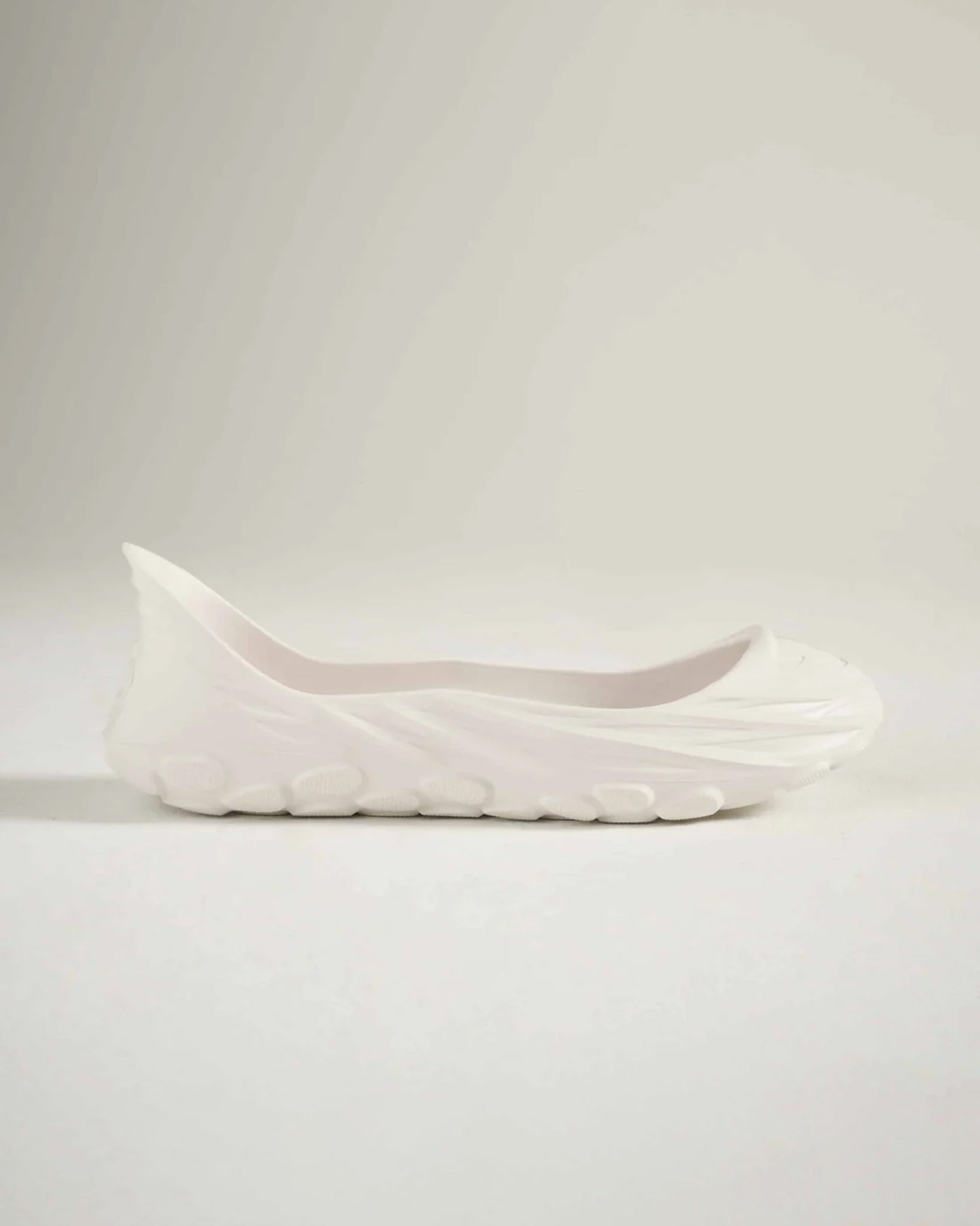 A sleek white slip-on shoe featuring a modern design and textured sole perfect for casual wear and comfort