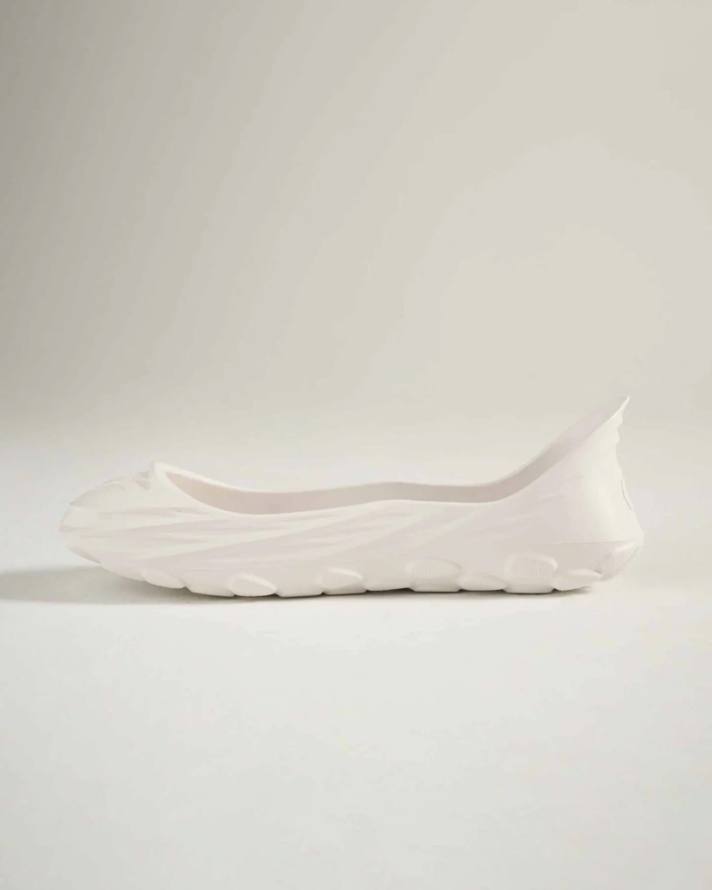 A sleek white sneaker with a minimalist design showcasing smooth contours and an innovative sole for comfortable wear