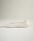 A sleek white sneaker with a minimalist design showcasing smooth contours and an innovative sole for comfortable wear