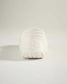 A minimalist white shoe showcasing a smooth rounded silhouette with a textured sole for traction