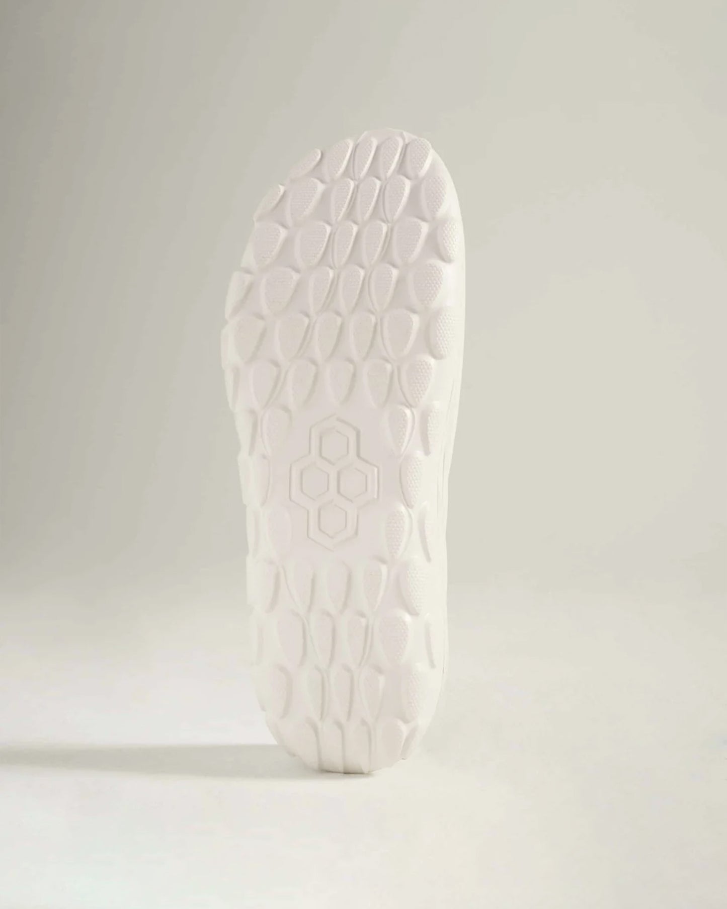 A close-up of a white shoe sole featuring a textured pattern designed for traction and support