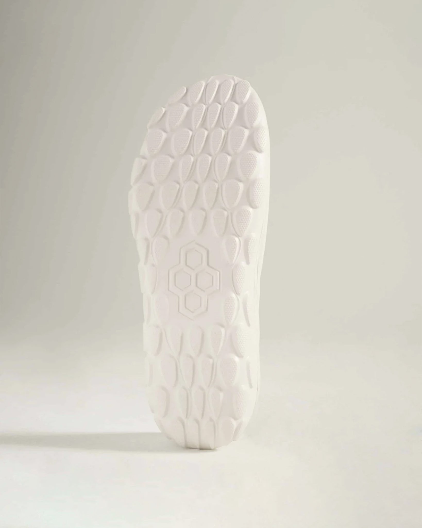 A close-up of a white shoe sole featuring a textured pattern designed for traction and support