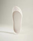 An elegant white shoe with a smooth finish and a structured design showcasing a unique sole and minimalistic aesthetic
