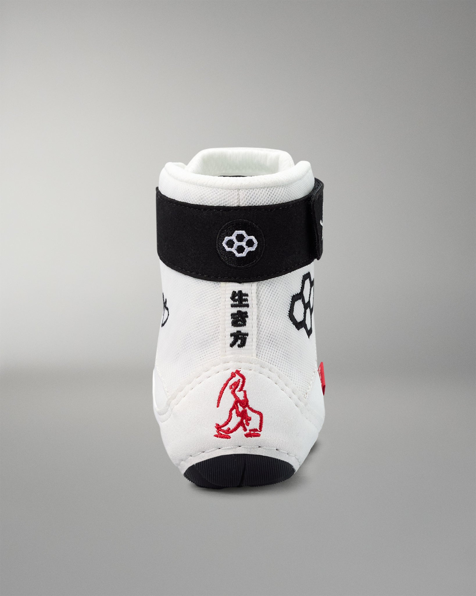 White wrestling shoe with black strap and red design on a gray background