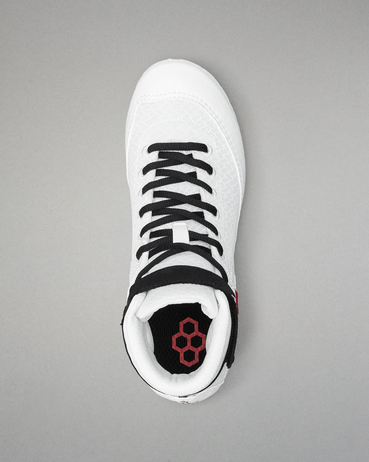 White wrestling shoe with black laces and red logo on a gray background