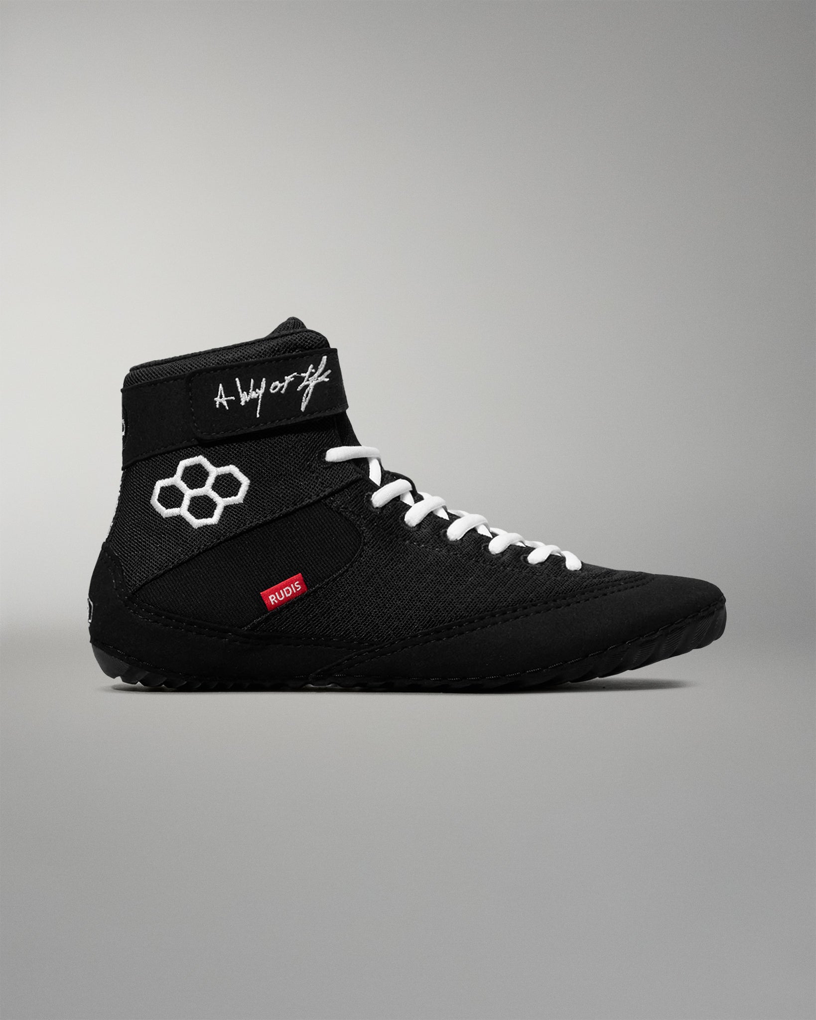 Black wrestling shoe with white laces on a gray background