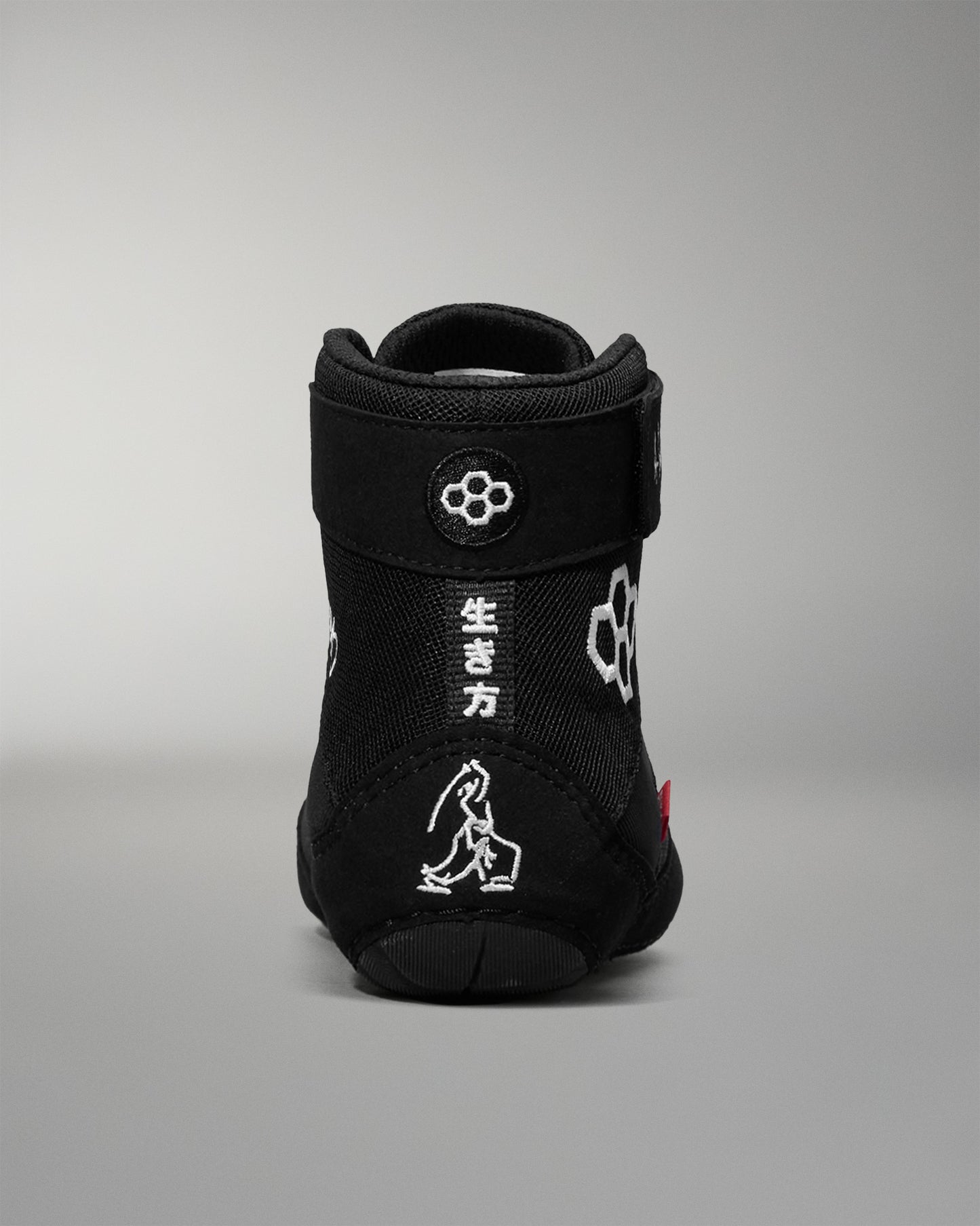 Black wrestling shoe with white designs on a gray background