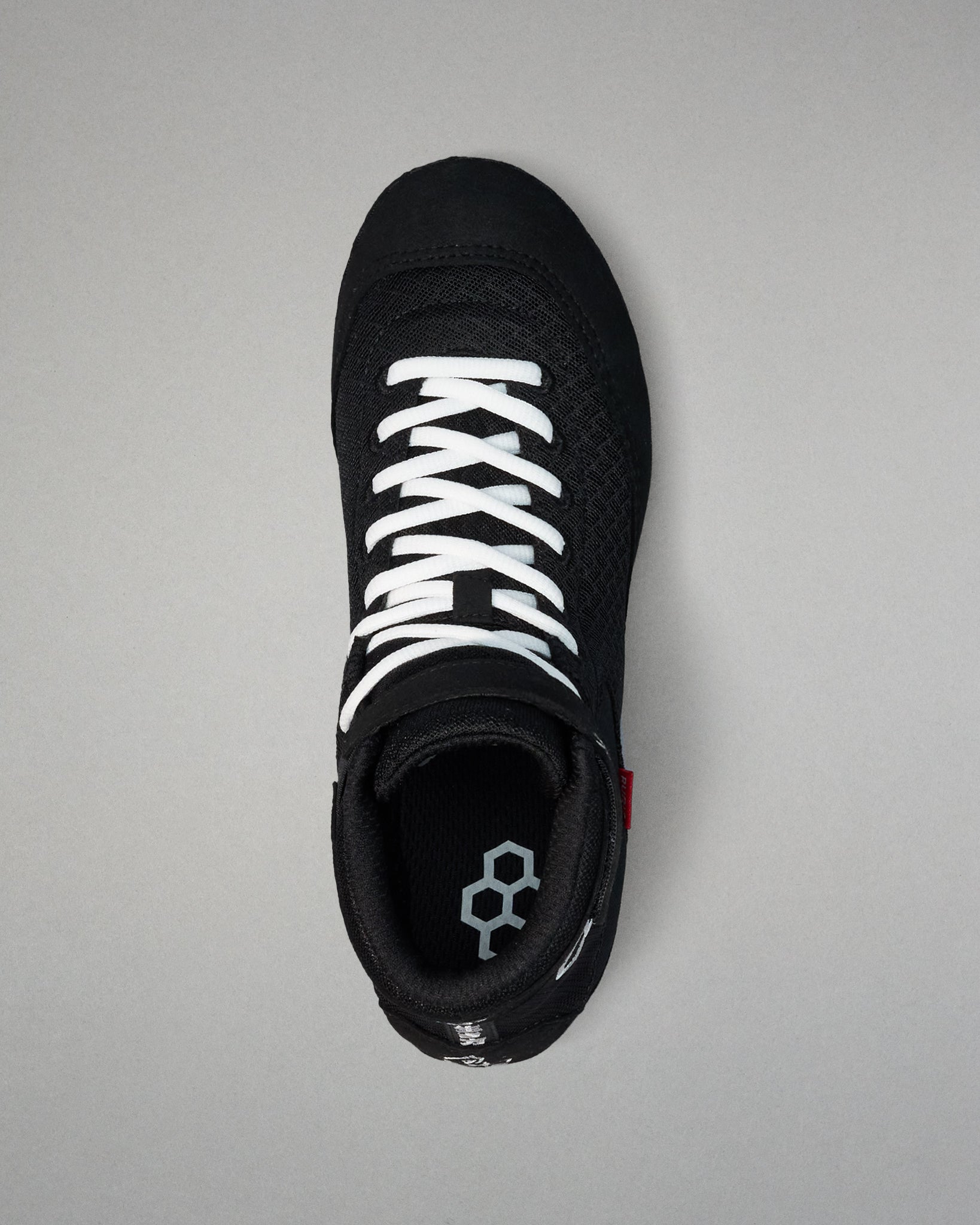 Black wrestling shoe with white laces on a gray background
