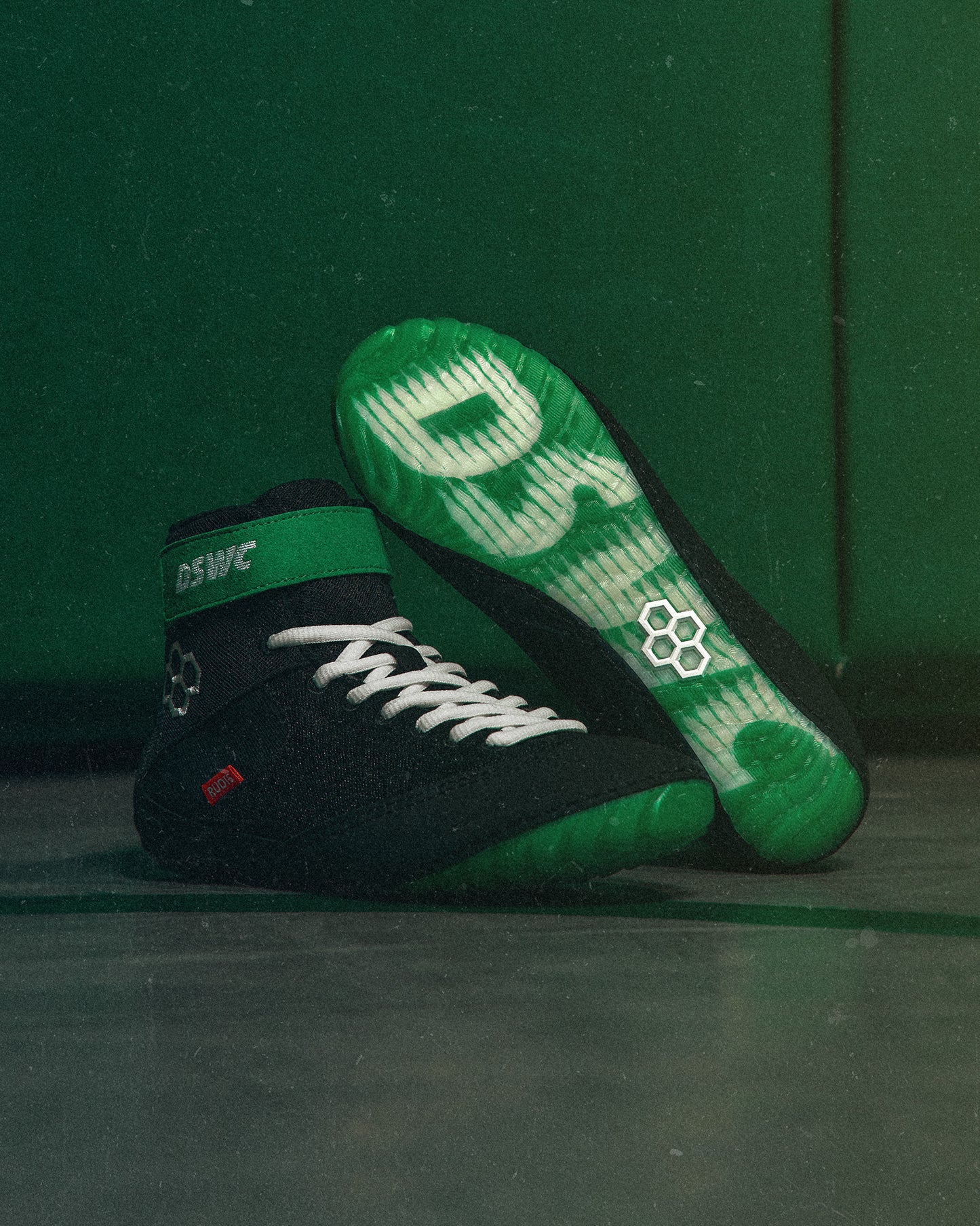Black and green wrestling shoes with visible branding on a green background